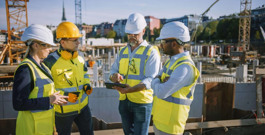 Diverse Team of Specialists Use Tablet Computer on Construction Site low res