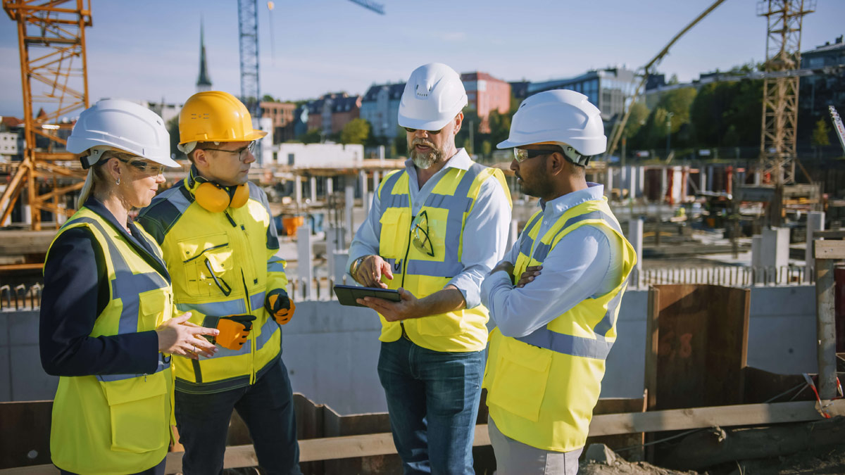 Diverse Team of Specialists Use Tablet Computer on Construction Site low res
